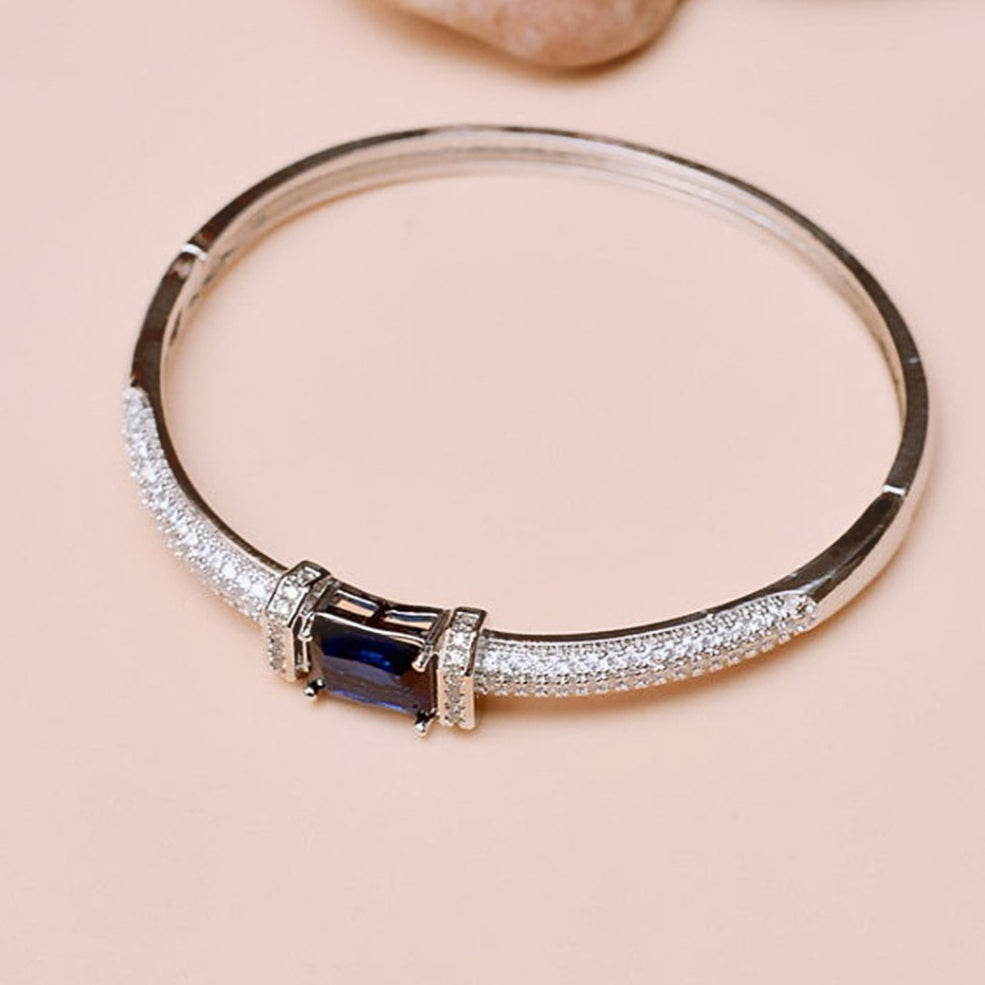 Silver bracelet with a blue gemstone on a beige background