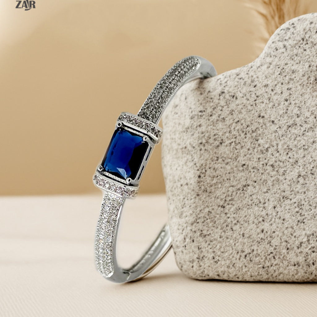 Silver bracelet with a blue gemstone on a beige surface
