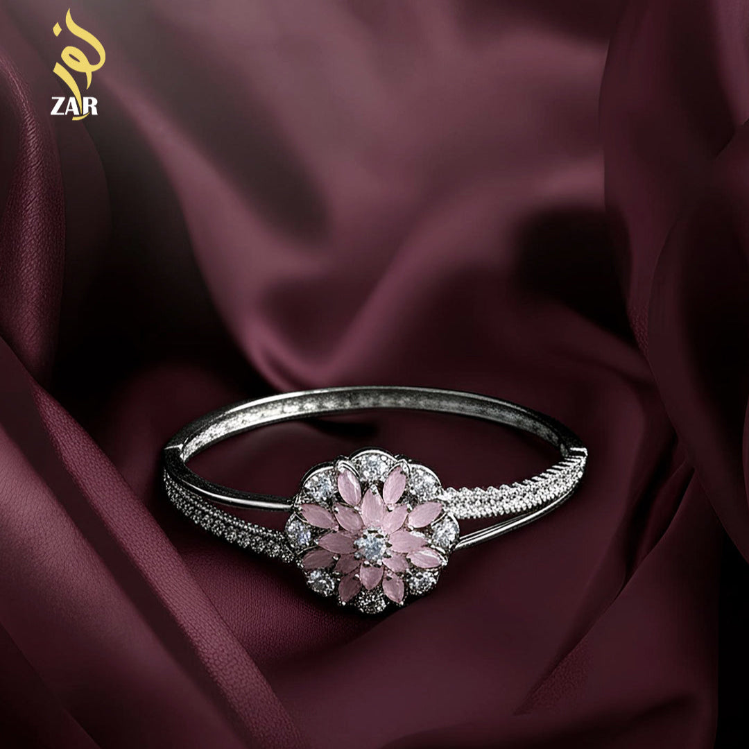 Silver ring with a pink gemstone on a dark fabric background
