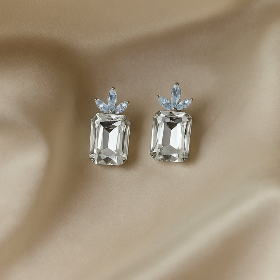 Pair of diamond earrings on a beige fabric background