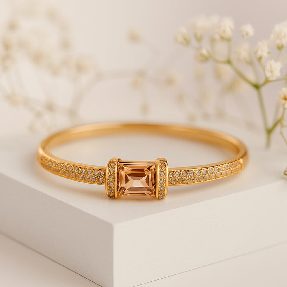 Gold bracelet with a central orange gemstone on a light background, featuring the ZAR brand.