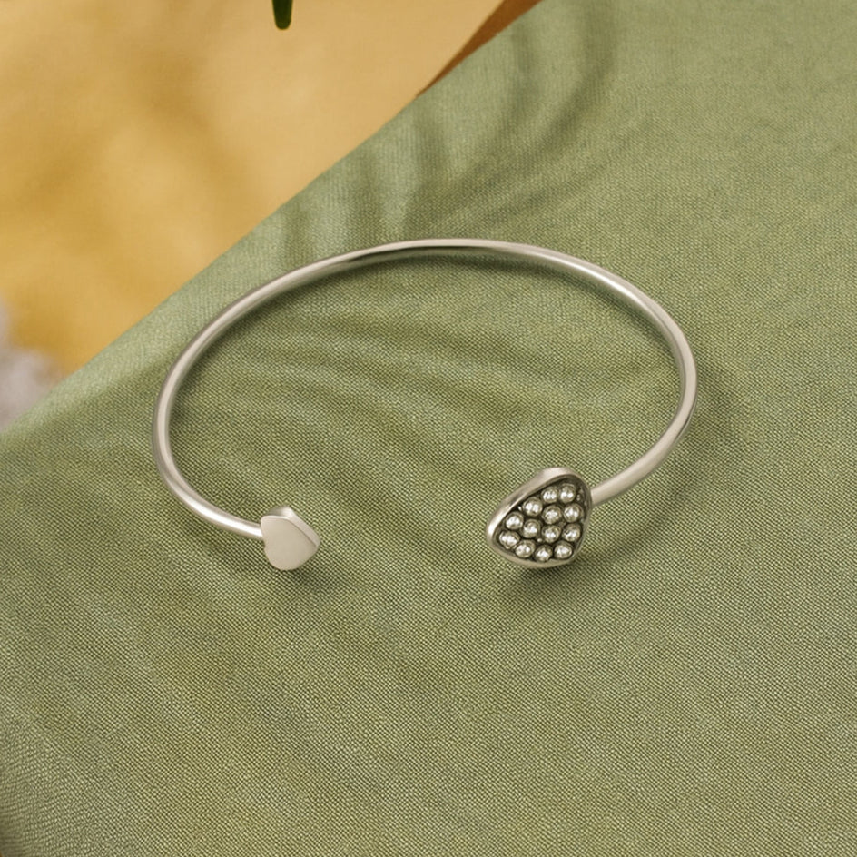 Silver bracelet with heart design on a green surface