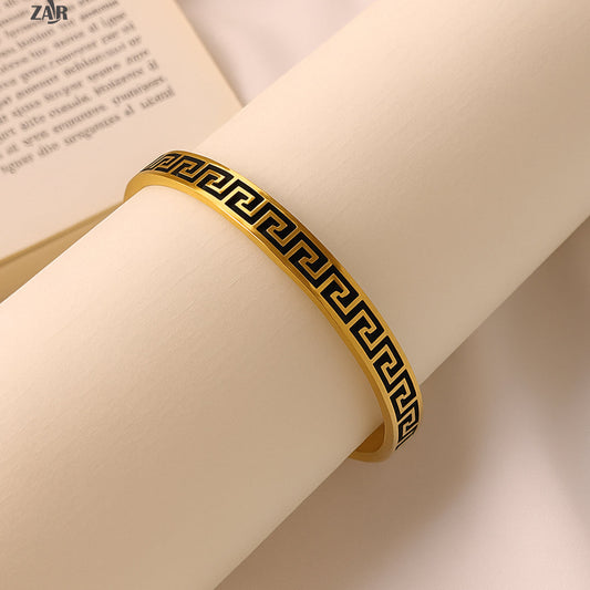Gold bracelet with black pattern on a rolled-up book