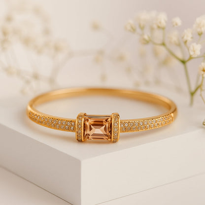 Gold bracelet with a central orange gemstone on a light background, featuring the ZAR brand.