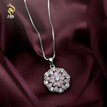 Silver necklace with a pink floral pendant on a dark fabric background